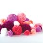 a pile of yarn pom-poms in red, purple, pinks