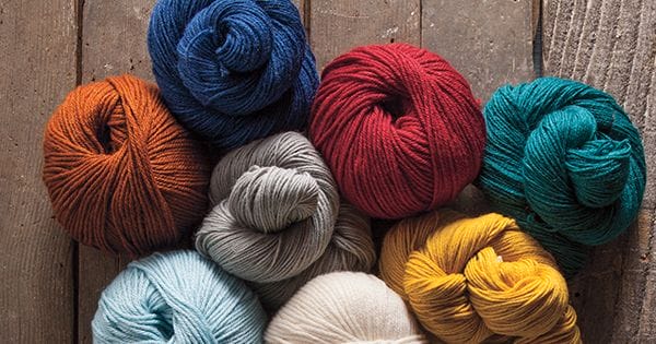 Gloss yarn balls grouped together on wooden planks.