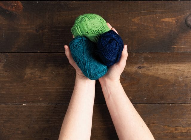 Hands holding small balls of Brava yarn