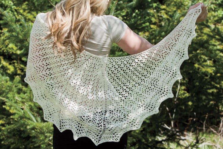 A woman faces away from the camera, showing off her cream-colored shawl