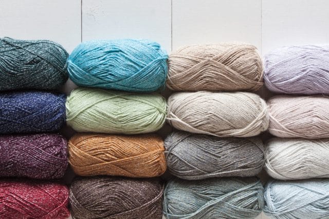 Alux Yarn: 16 skeins of colorful yarn lay on a white background