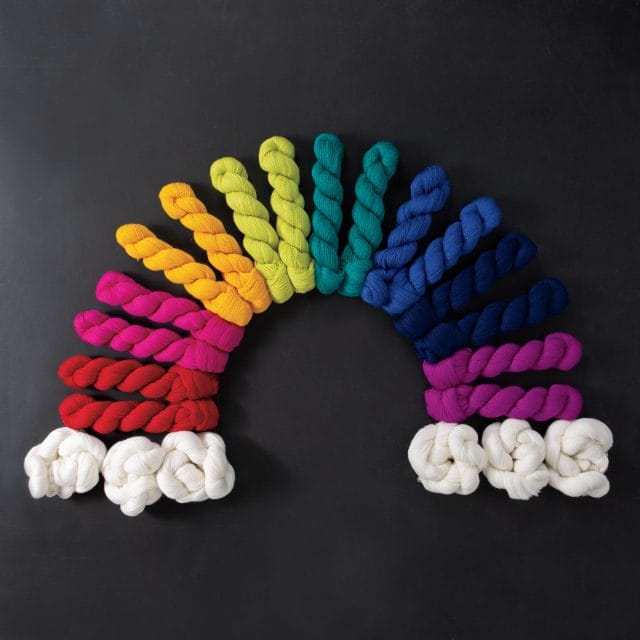9 colorways of Knit Picks Shimmer lace yarn in the shape of a rainbow.