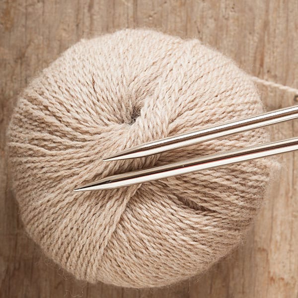 Sharp metal needles on top of a ball of yarn