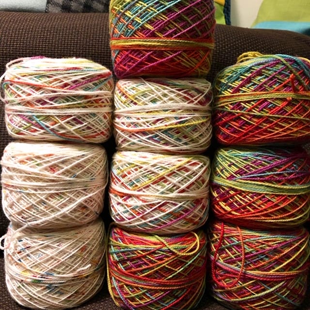 Stacks of caked yarn, going from light-colored to multicolored.
