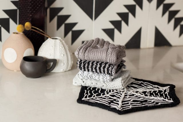 A stack of gray, white, and black dishcloths on a countertop.