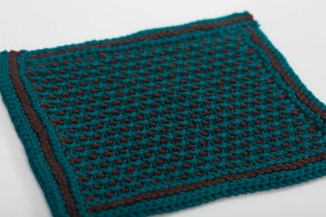 A teal and brown knitted dishcloth with an alternating color pattern.