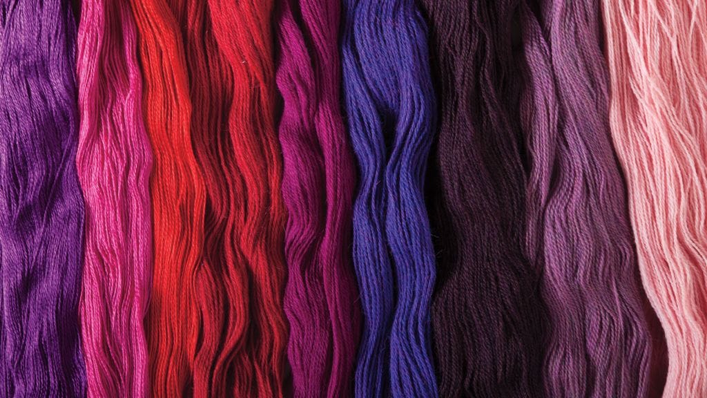 Yarn laying across the entire image in A gradient of purple-pink-red-blue-black-purple-pink