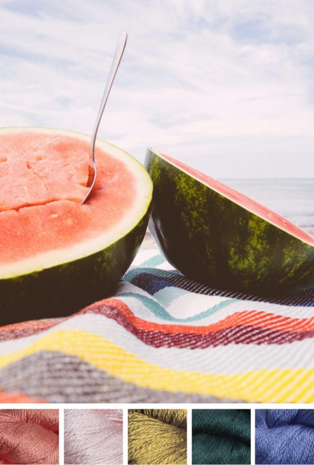 A mouth-watering watermelon cut in half with a spoon inside one half, on a colorful woven blanket at the beach. Beneath is a color palette that consists of five yarn swatches in coral, light pink, golden green, forest green, and periwinkle.