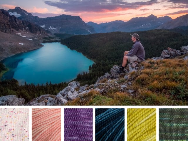 A beautiful mountain vista at sunset, overlooking a deep blue lake. A hiker sits on a rocky cliff that is covered with shrubs. Beneath is a color palette that consists of six yarn swatches in off-white with multicolored speckles, peachy-pink, warm purple, varigated indigo blue with streaks of lighter blue, bright citron yellow-green, and a variegated dark green with stripes of lighter blue-green.