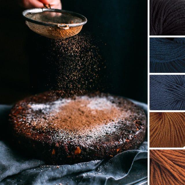 An autumn color palette: To the left, the inspiration photo consists of a dark blue background where a hand is shaking cocoa powder onto a rustic chocolate cake. To the right, five yarn swatches from Gloss yarn in the following colors: Navy blue, dark sea blue, gray blue, gold, and rust.