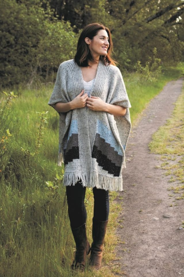 A model wears the Oakwood poncho, an accessory pattern knit in Wool of the Andes Tweed yarns