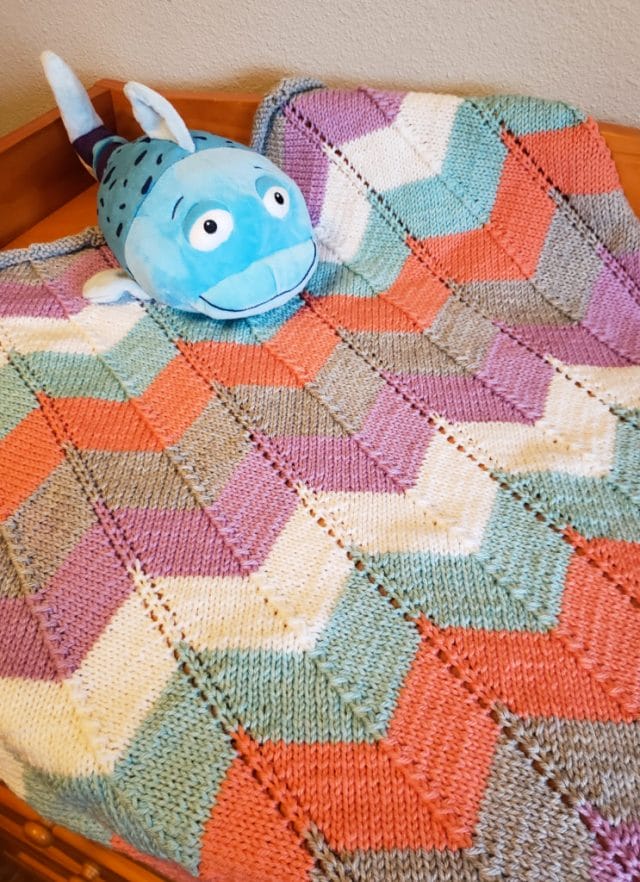 A chevron baby blanket, knitted in bright colors of Swish Worsted.