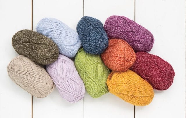 On a white board background, a pile of Kindred yarn in various colors.