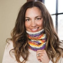 A woman wears a striped knitted cowl around her neck