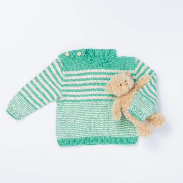 A knitted baby sweater holding a teddy bear