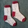 A pair of hand knit socks in red and white.