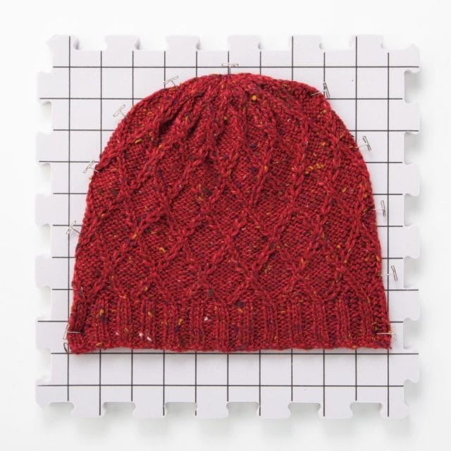 A knitted hat on a blocking mat