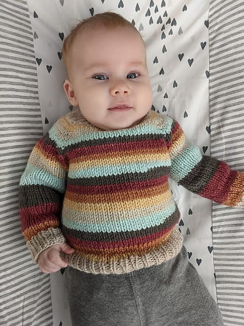 Flax sweater by Ravelry User Vyndree. A baby wears a striped knitted sweater.