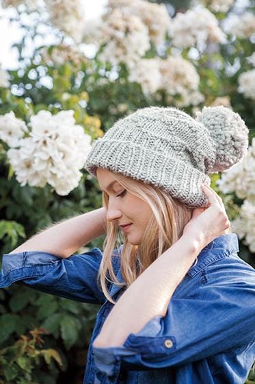 A gray knitted hat with a large gray yarn pom-pom