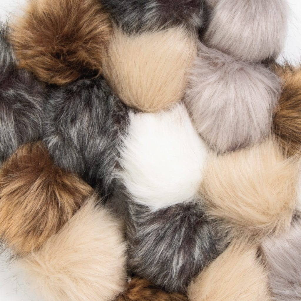 A pile of faux fur pom-poms in neutral colors