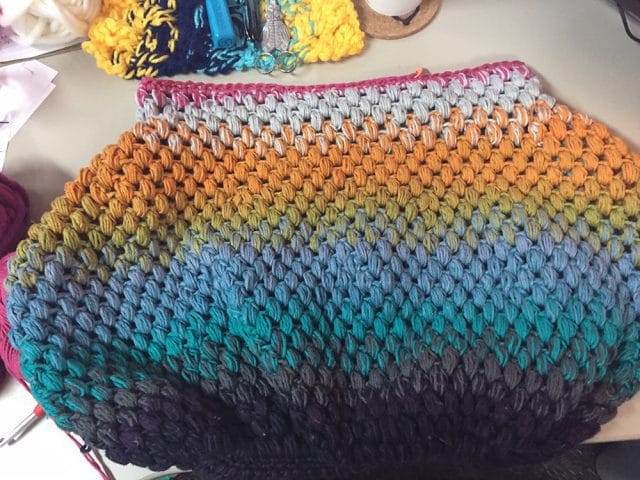One of Heather's Unfinished Objects: A crocheted bag in a gradient of gray, orange, green, blue, teal, purple, and black.