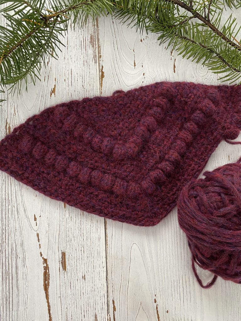 A top-down view of a partially-finished crochet project in dark red Wonderfluff Yarn