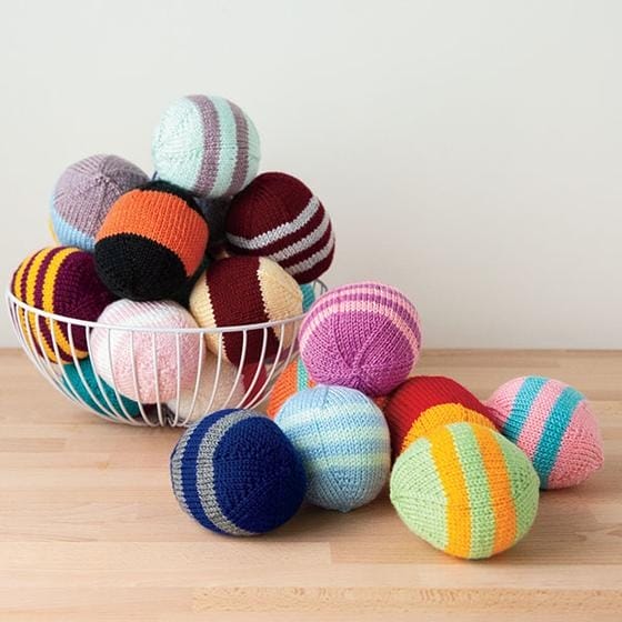 hand-knitted striped balls in multiple colors piled in a basket