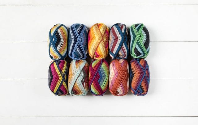 10 skeins of self-striping sock yarn are laid out in two rows of five on a white background. 