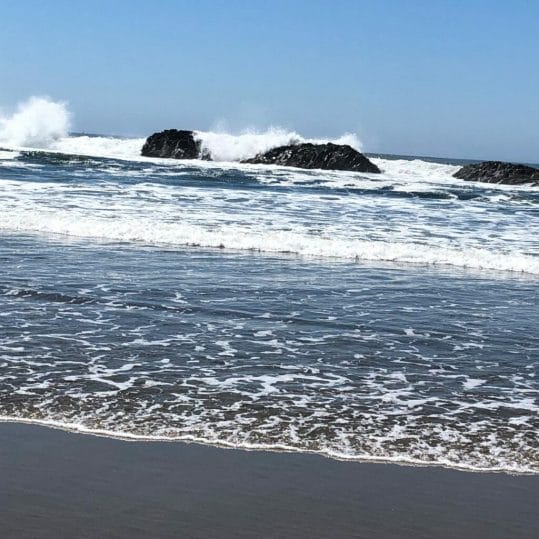 Ocean waves hit large rocks off the coast.