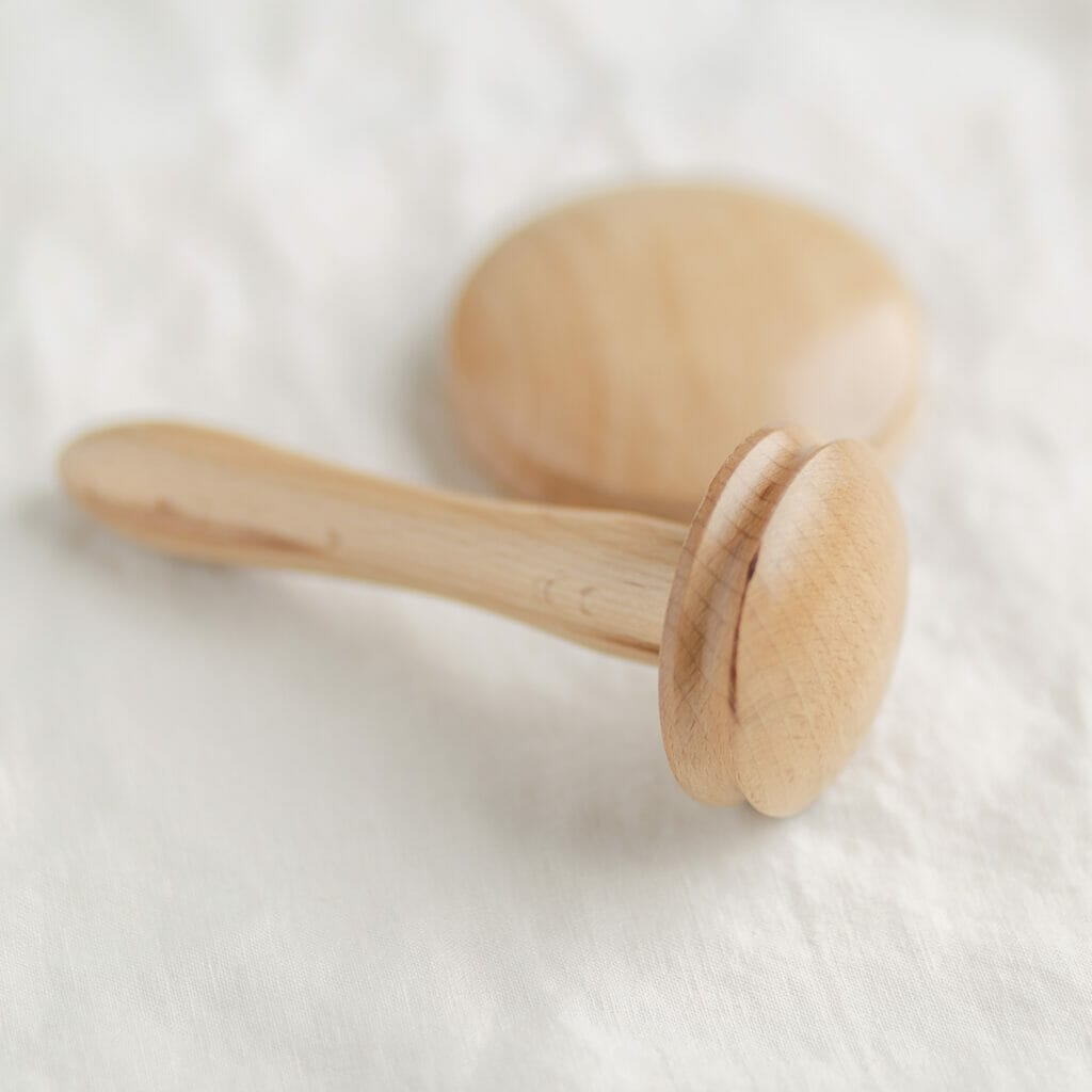 a darning mushroom with a handle and smaller top is laid next to a larger mushroom top
