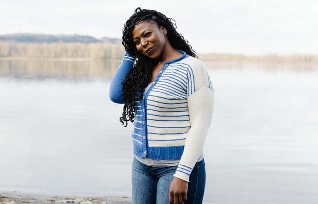 a mid-sized Black woman wears a cardigan that isn't too tight or very loose. 