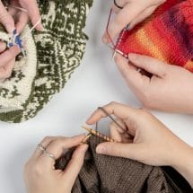 A top-down photo of multiple people knitting together.