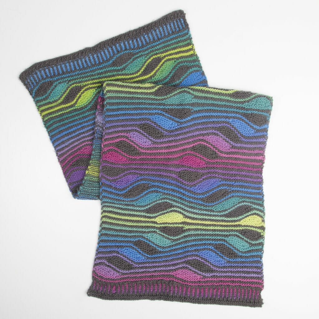 A completed handknit wrap with squiggly stripes in neon shades and dark gray