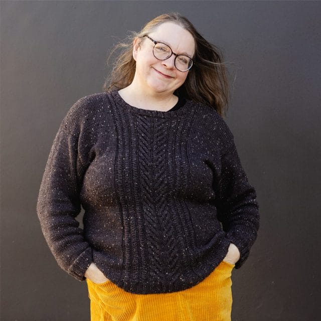 A woman wearing a dark brown cabled sweater