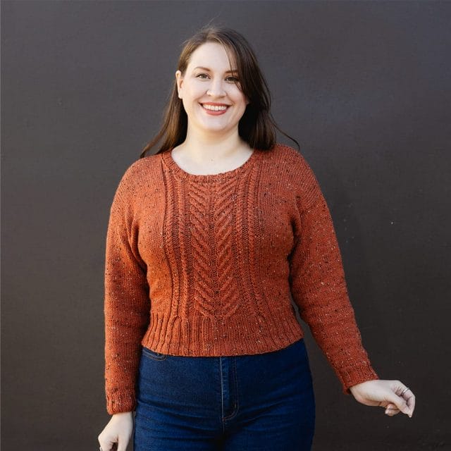 A woman wearing an orange cabled sweater