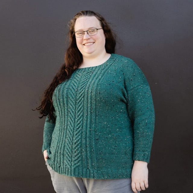 A woman wearing a teal cable sweater