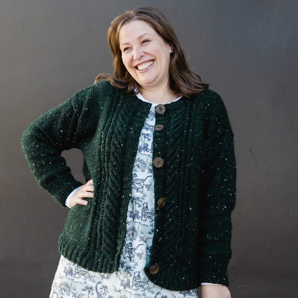 A woman wearing a dark green cabled cardigan